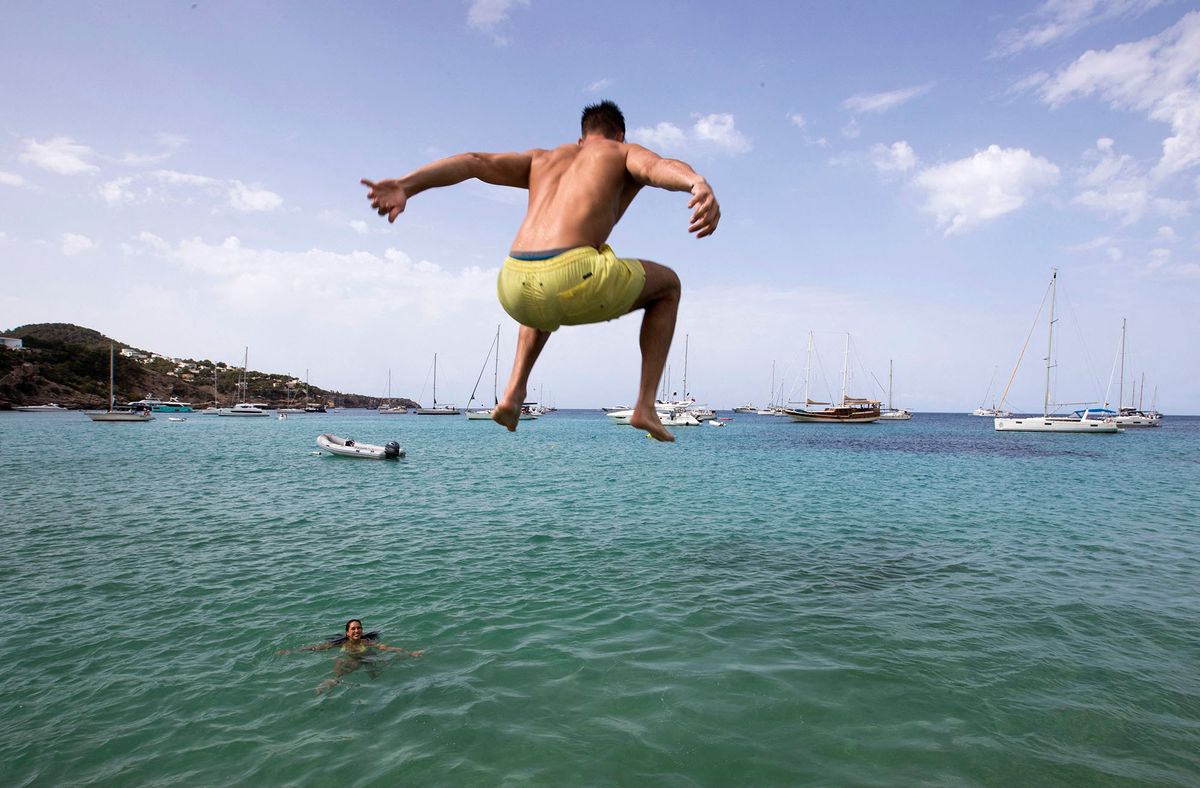 A man jumps into the sea at Cala Tadira beach near Sant Josep de Sa Talaia on the Balearic island of Ibiza on August 24, 2021 (Photo by JAIME REINA / AFP)