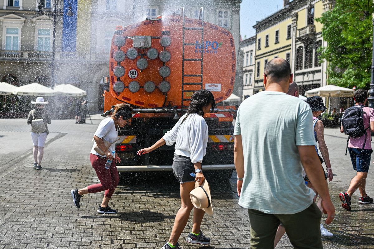 KRAKOW, POLAND - JUNE 29: People cool themselves by a city truck with a water curtain due to high temperatures in Krakow, Poland on June 29, 2022. the Polish Institute of Meteorology and Water Management has issued orange heat warnings (the middle level on a three-tier scale) over parts of Poland as temperatures reach 35 Celcius degrees. Omar Marques / Anadolu Agency (Photo by Omar Marques / ANADOLU AGENCY / Anadolu Agency via AFP)