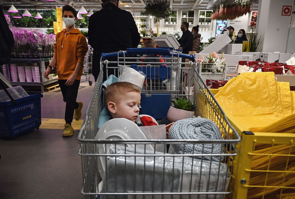 A child sits in a shopping trolley while his parents shop in a store in Moscow on December 28, 2020, amid the crisis linked with the Covid-19 pandemic caused by the novel coronavirus. - Russia confirmed 27,787 new daily Covid-19 cases including 6,253 in Moscow. (Photo by Alexander NEMENOV / AFP)