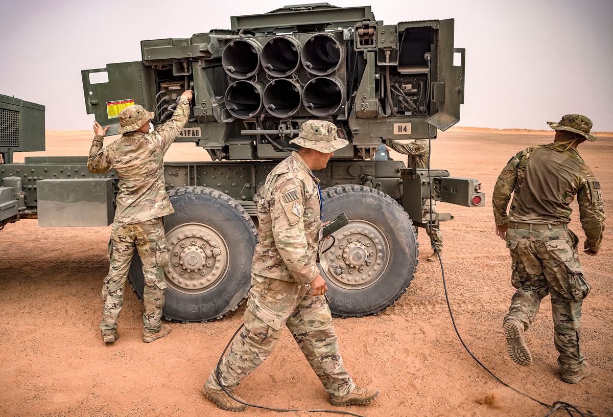 US soldier walk past an M142 High Mobility Artillery Rocket System (HIMARS) launcher vehicle, during the "African Lion" military exercise in the Grier Labouihi region in southeastern Morocco on June 9, 2021. (Photo by FADEL SENNA / AFP)