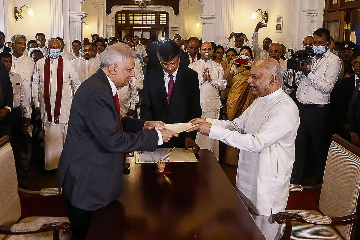 Sri Lakan President Ranil Wickremesinghe (L) swears in Dinesh Gunawardena (R) as Sri Lanka's new Prime Minister, at the prime minister office in Colombo on July 22, 2022. (Photo by AFP)