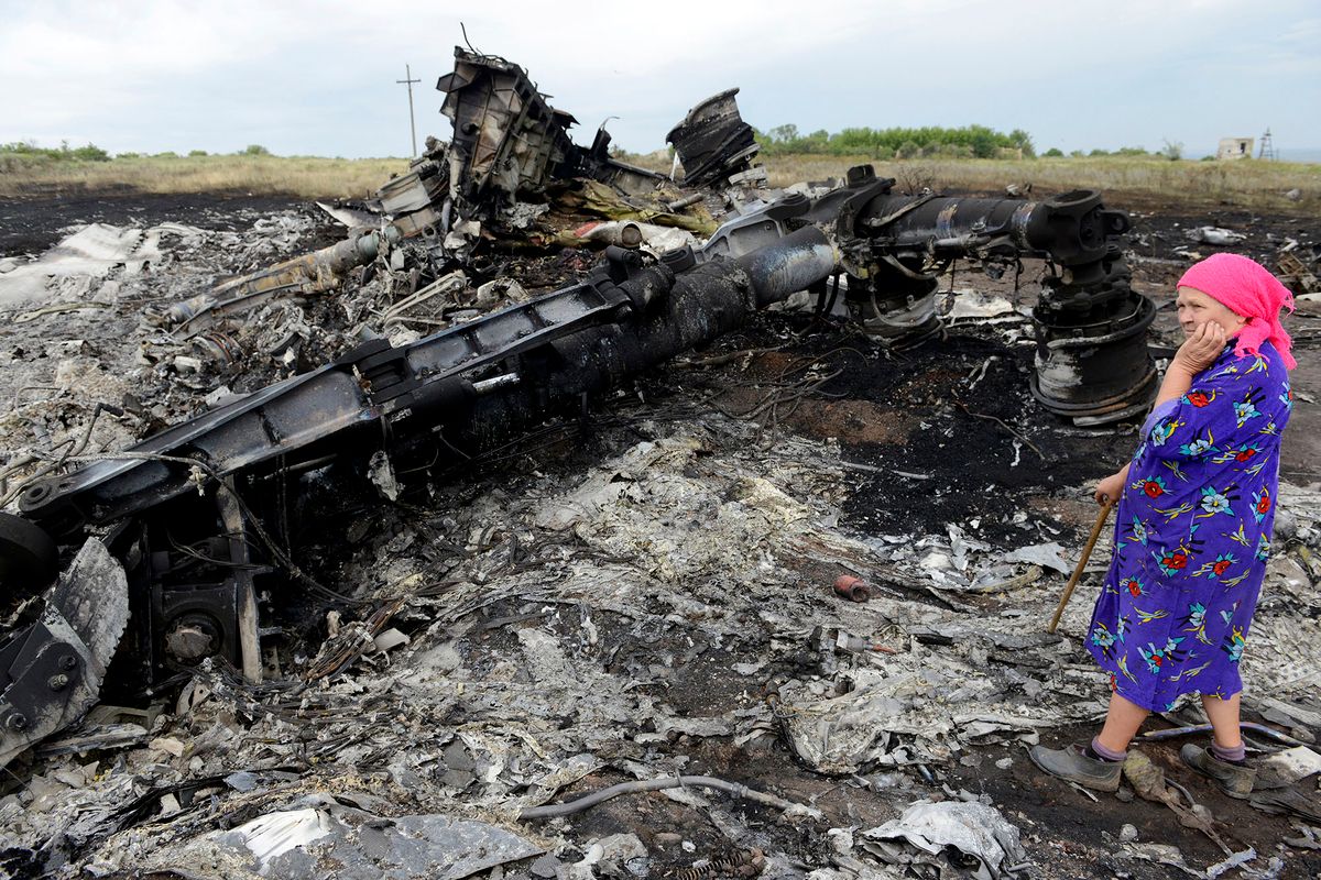 A local resident stands among the wreckage at the site of the crash of a Malaysia Airlines plane carrying 298 people from Amsterdam to Kuala Lumpur in Grabove, in rebel-held east Ukraine, on July 19, 2014. Ukraine and pro-Russian insurgents agreed on July 19 to set up a security zone around the crash site of a Malaysian jet whose downing in the rebel-held east has drawn global condemnation of the Kremlin. Outraged world leaders have demanded Russia's immediate cooperation in a prompt and independent probe into the shooting down on July 17 of flight MH17 with 298 people on board. AFP PHOTO/ ALEXANDER KHUDOTEPLY (Photo by Alexander KHUDOTEPLY / AFP)
