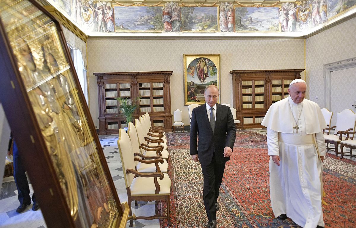 This photo taken and handout on July 4, 2019 by the Vatican Media shows Pope Francis (R) and Russian President Vladimir Putin (C) walking by an icon (L) offered by Putin to the Pope as they exchange gifts during a private audience at the Vatican. - Russian President Vladimir Putin arrived in Rome for a lightning visit including talks with the pope and Italy's populist government, which has called for an easing of sanctions despite Moscow's ongoing crisis with the West. (Photo by Handout / VATICAN MEDIA / AFP) 