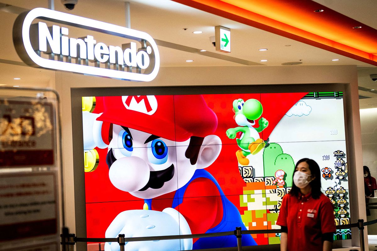 An employee wearing a face mask stands next to a screen displaying a character of Nintendo game Super Mario at a store for Japanese games giant Nintendo in Tokyo on February 3, 2022. (Photo by Behrouz MEHRI / AFP)