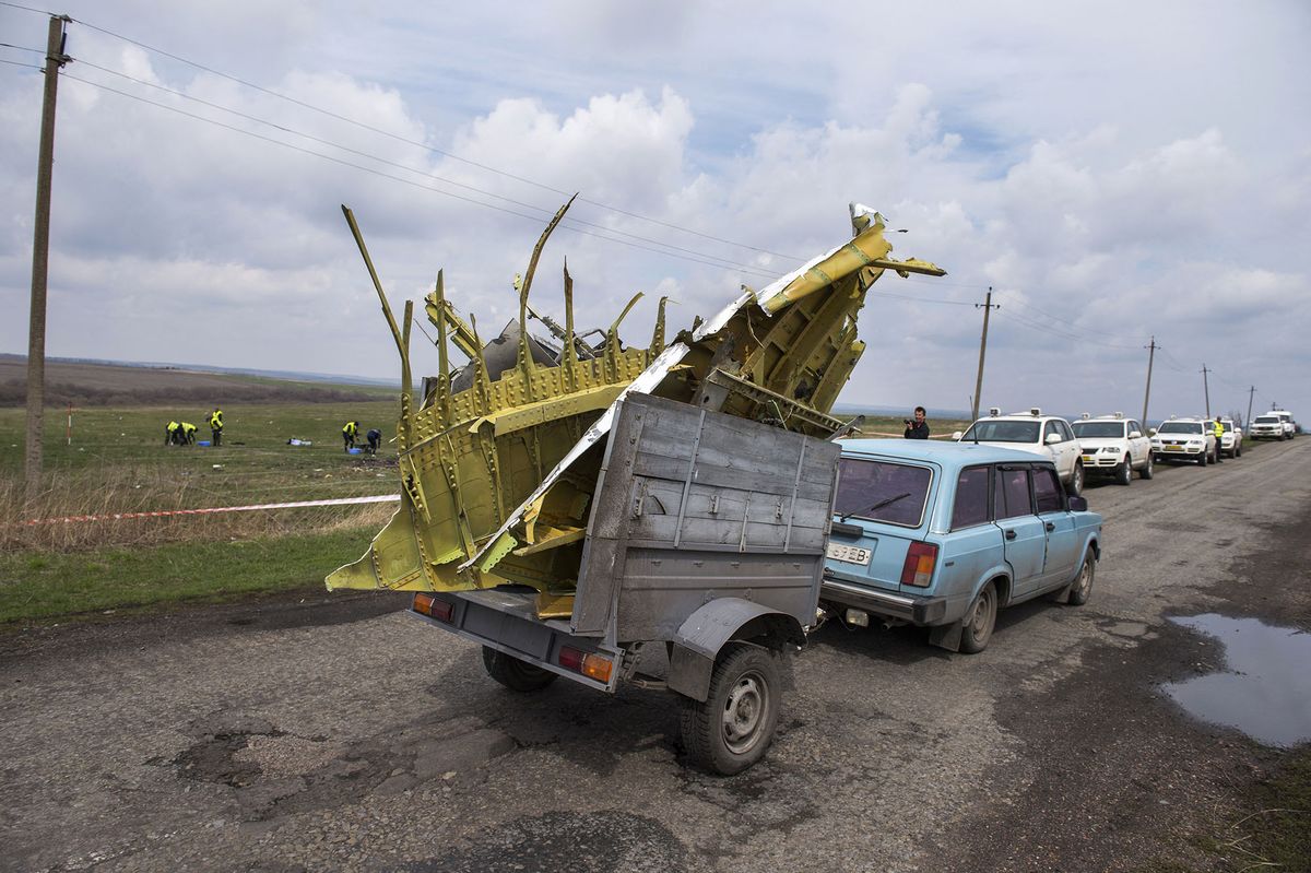 A person drives a vehicle carrying debris of the aircraft in a trailer at the MH17 plane crash site on April 16, 2015 near the village of Grabove in the self-proclaimed Donetsk People's Republic (DNR) as Dutch and international investigators are renewing their search for body parts and debris at in restive eastern Ukraine, including at a location previously considered unsafe, the team's chief announced on the eve.  All 298 passengers and crew onboard the Malaysia Airlines jetliner -- the majority of them Dutch -- died when it was shot down over war-torn eastern Ukraine last year. AFP PHOTO / ODD ANDERSEN (Photo by Odd ANDERSEN / AFP)