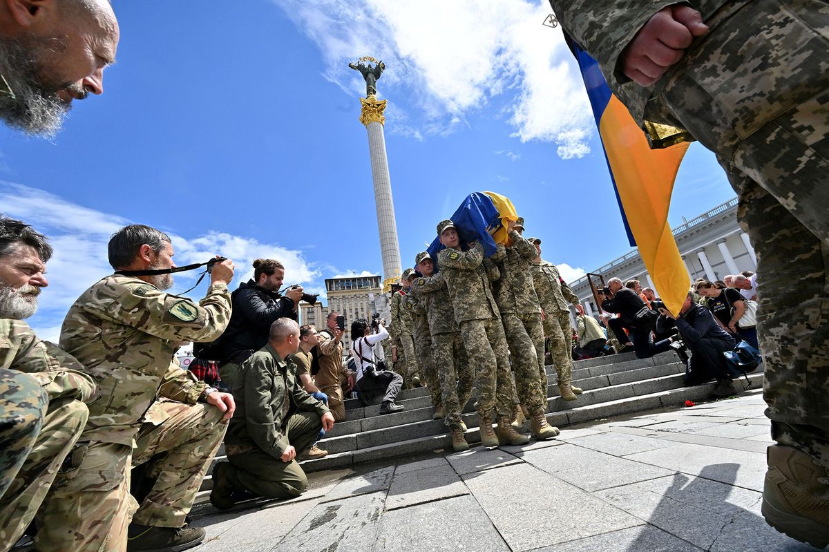 Ukrainian servicemen kneel down as fellow soldiers carrry the coffin of their comrade Oleh Kutsyn, commander of the "Karpatska Sitch" battalion killed during the war against Russia, during a funeral ceremony at Kyiv's "Maidan" Independence Square on June 22, 2022. (Photo by Sergei SUPINSKY / AFP)