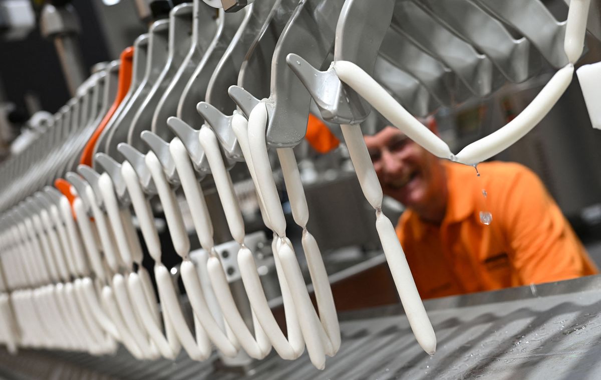 13 May 2022, Hessen, Frankfurt/Main: Markus Schließer, development engineer, stands at the booth of Handtmann-Maschinenfabrik from Biberach at a ConProLink system from which sausages are hanging on which a vegan casing has been injected. The Frankfurt meat industry trade show IFFA (May 14-19) is increasingly focusing on plant-based proteins. More than 200 of the 860 exhibitors will inform visitors about technologies and solutions on meat alternatives. Photo: Arne Dedert/dpa (Photo by ARNE DEDERT / DPA / dpa Picture-Alliance via AFP)