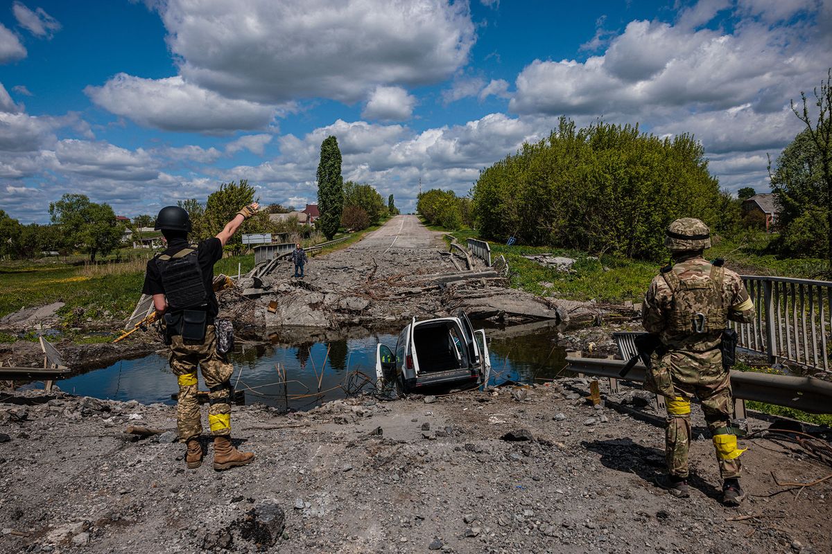 Soldiers of the Kraken Ukrainian special forces unit talk to a man at a destroyed bridge on the road near the village of Rus'ka Lozova, north of Kharkiv, on May 16, 2022. - Ukraine has said its troops have regained control of territory on the Russian border near the country's second-largest city of Kharkiv, which has been under constant fire since Moscow's invasion began. (Photo by Dimitar DILKOFF / AFP)