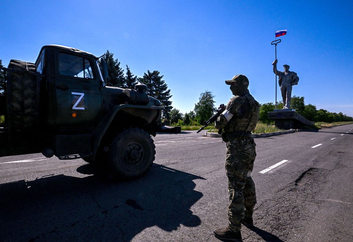 A russian serviceman stands guard next to monument to metallurgists with a Russian flag on the top, at the entrance of Mariupol on June 12, 2022, amid the ongoing Russian military action in Ukraine. (Photo by Yuri KADOBNOV / AFP)