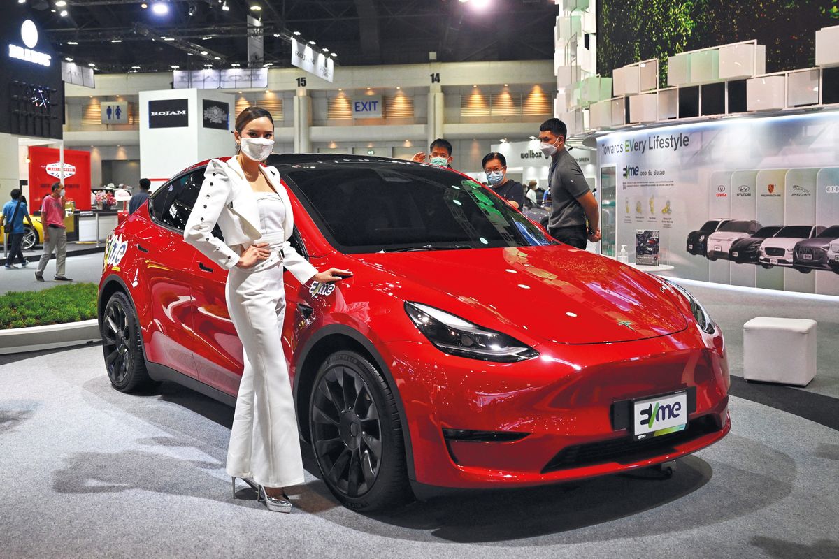 A model promotes the Tesla Model Y electric car at the Bangkok International Motor Show in Bangkok on March 24, 2022. (Photo by Lillian SUWANRUMPHA / AFP)