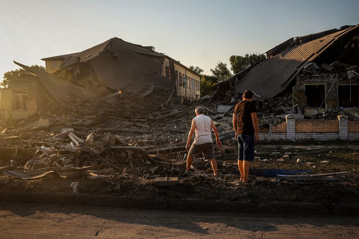 Local residents look at a destroyed school building following a missile strike in Druzhkivka, Donetsk region on August 30, 2022, amid the Russian invasion of Ukraine. - Russia’s invasion caused more than two million children to leave the country and displaced three million internally between February and June 2022, according to UNICEF. 
