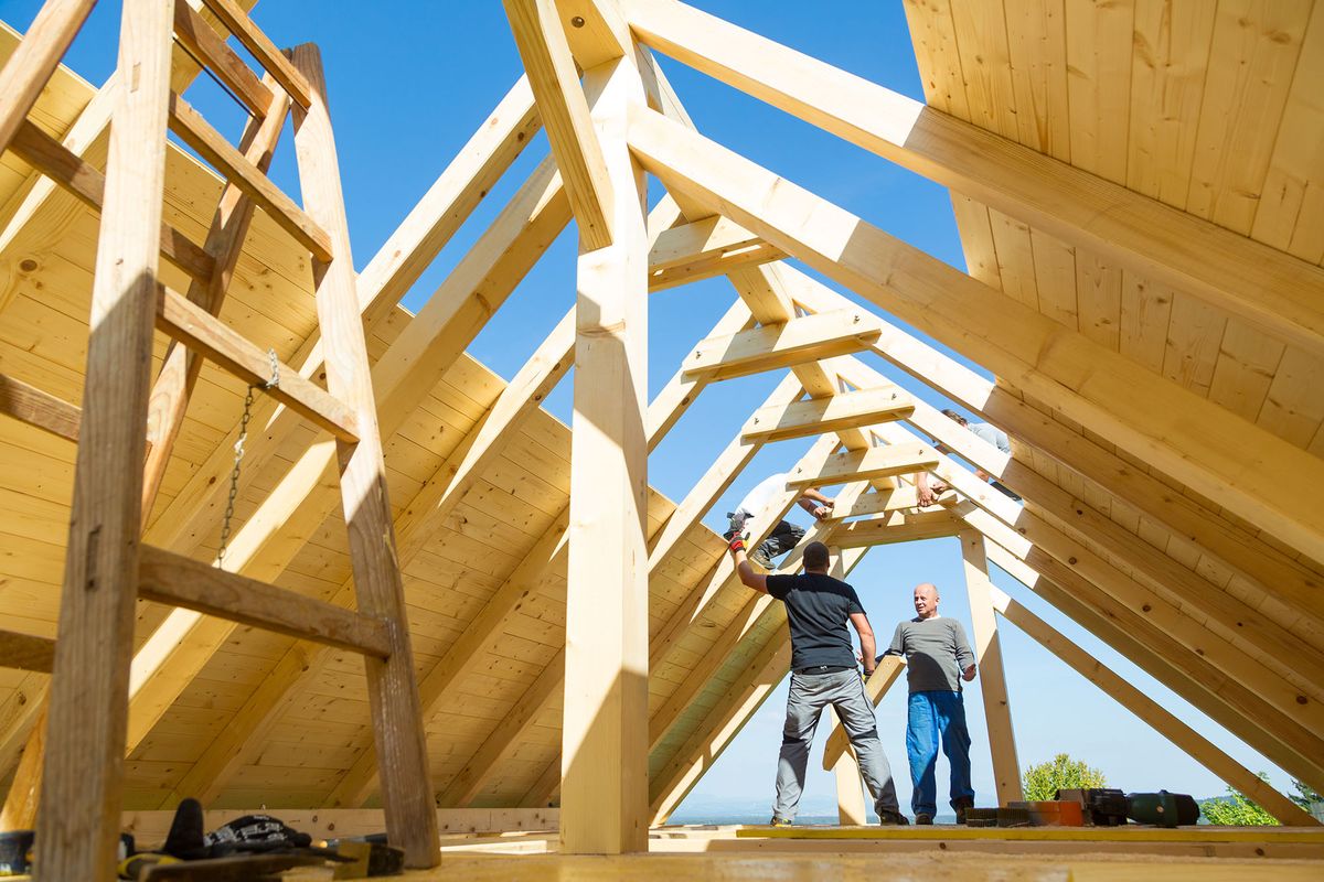Roof tető ács munkások építkezés builders mounting prefabricated wooden roof construction. fa szerkezet építőipar lakás ház otthon Construction industry concept.