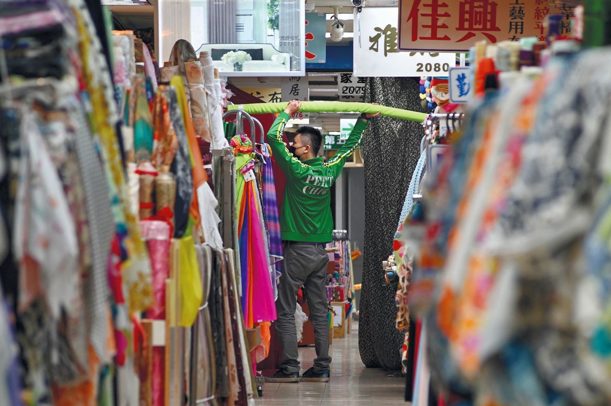 A man sorts out cloths at a fabric store in the Yongle Market in Taipei on July 14, 2021. (Photo by Sam Yeh / AFP)