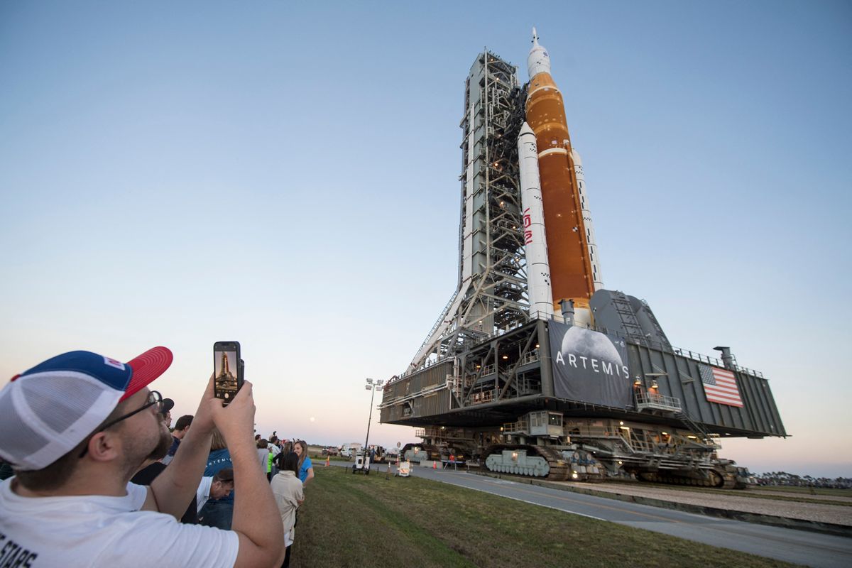 In this NASA handout photo invited guests and NASA employees take photos as NASA's Space Launch System (SLS) rocket with the Orion spacecraft aboard is rolled out of High Bay 3 of the Vehicle Assembly Building for the first time, March 17, 2022, at NASA's Kennedy Space Center in Florida. - NASA's massive new rocket began its first journey to a launchpad on March 17, 2022 ahead of a battery of tests that will clear it to blast off to the Moon this summer. 