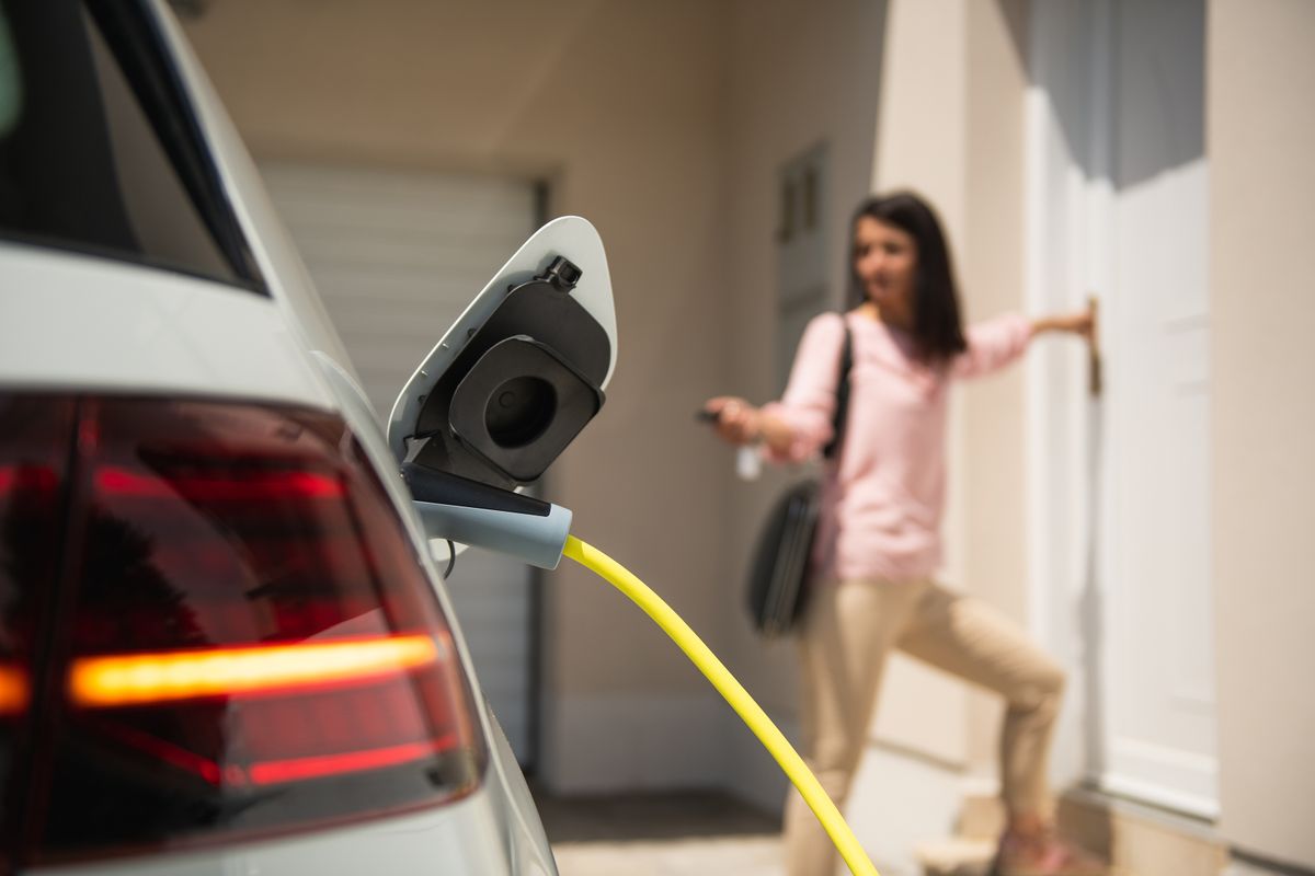 Close,Up,Of,A,Electric,Car,Charger,With,Female,Silhouette