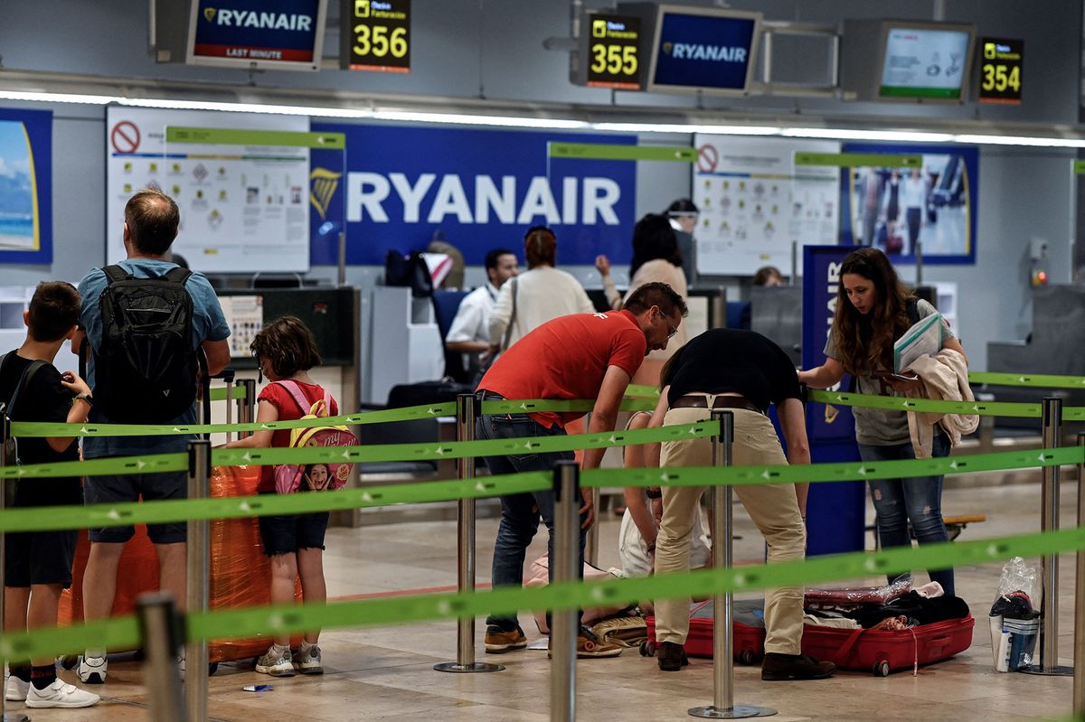 Passengers stand near the Ryanair check-in counters during a strike at Adolfo Suarez Madrid Barajas airport Madrid on June 24, 2022. - A strike by staff members at Ryanair and Brussels Airlines over pay and working conditions forced the cancelation of dozens of flights in Europe at the start of the peak summer travel season. In Spain, where Ryanair employs 1,900 people, no flights were cancelled except those heading to Belgium. (Photo by OSCAR DEL POZO / AFP)
