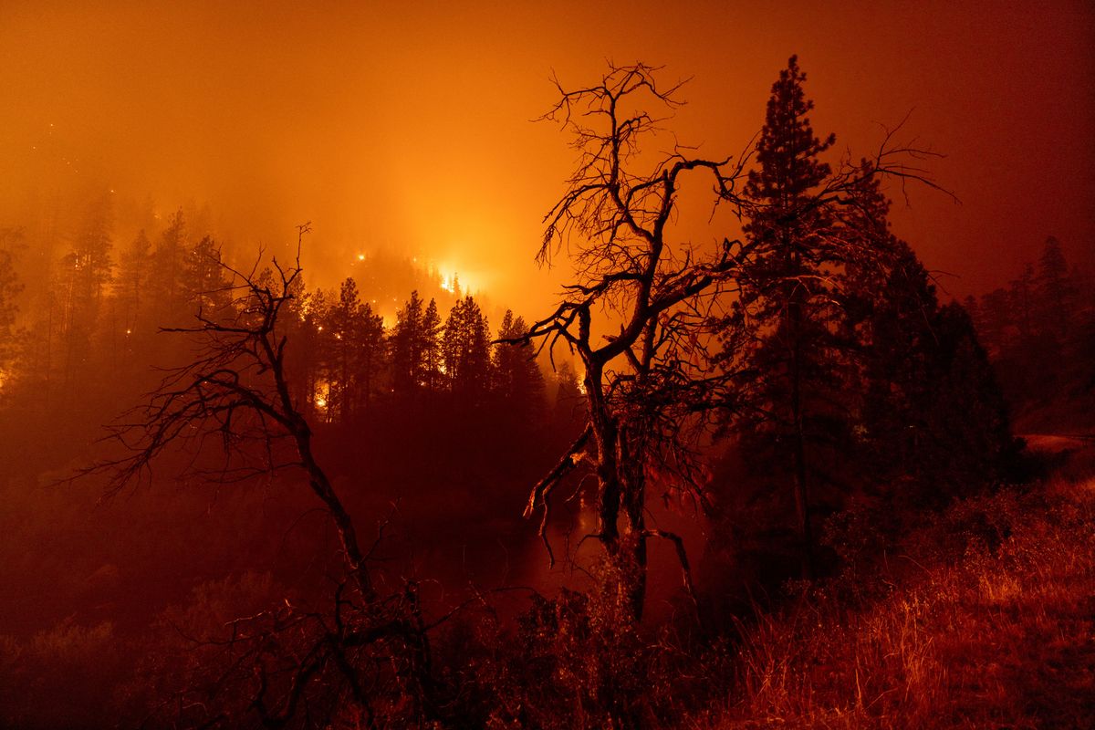 Flames burn to the Klamath River during the McKinney Fire in the Klamath National Forest northwest of Yreka, California, on July 31, 2022. - The largest fire in California this year is forcing thousands of people to evacuate as it destroys homes and rips through the state's dry terrain, whipped up by strong winds and lightning storms.The McKinney Fire was zero percent contained, CalFire said, spreading more than 51,000 acres near the city of Yreka. (Photo by DAVID MCNEW / AFP)