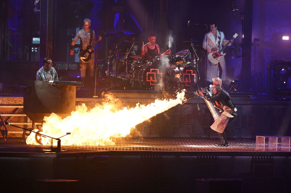 18 June 2022, North Rhine-Westphalia, Duesseldorf: Rammstein lead singer Till Lindemann (r) fires a flamethrower at band member Christian Lorenz (l) on stage during the track "Mein Teil". Rammstein are on tour in Germany with their new album "Zeit". Photo: Malte Krudewig/dpa