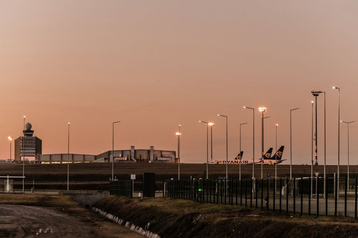 Repülőgépek parkolnak a Budapest Liszt Ferenc Nemzetközi Repülőtér betonján. Balra a repülőtér irányítótornya.
