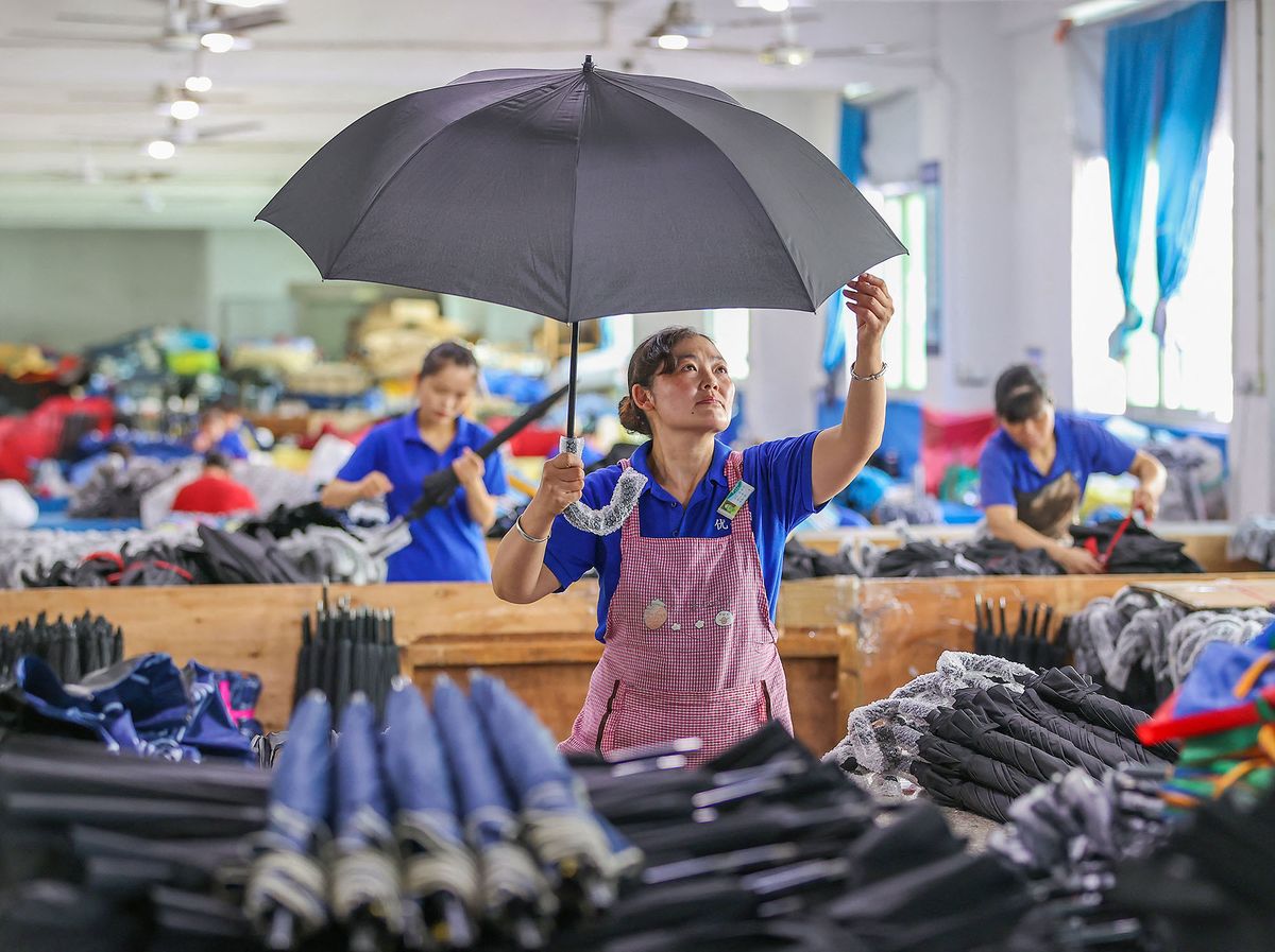 This photo taken on June 24, 2022 shows a worker producing umbrella at a factory in Jinjiang in China's eastern Fujian province. (Photo by STR / ZH0097 / AFP) (Photo by ZH0097 / China Xtra via AFP)