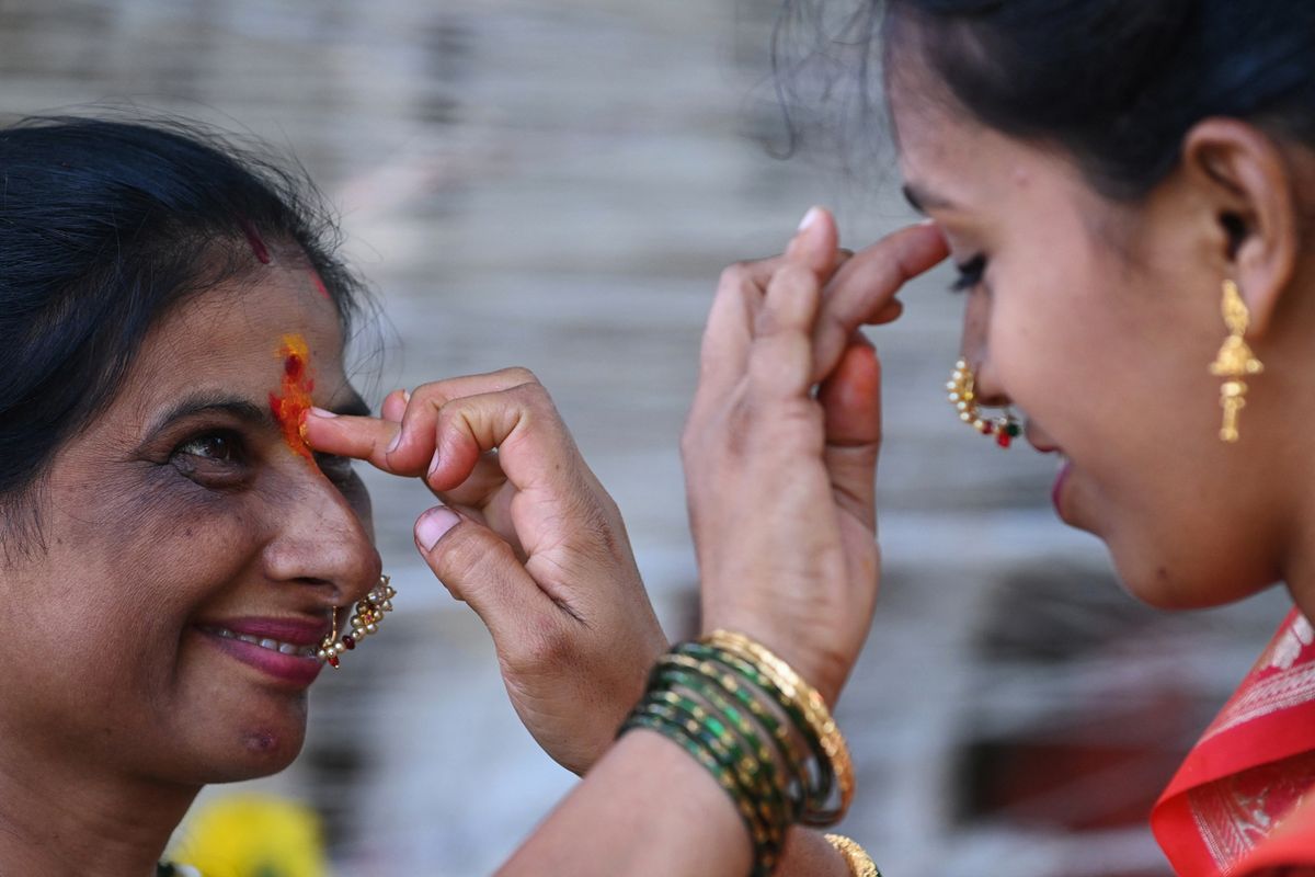 Married Hindu women apply vermillion powder on their forehead, a mark of marriage among Hindu women, after circumambulating around a banyan tree while tying a thread on the occasion of 'Vata Savitri Purnima', in Mumbai on June 14, 2022. 