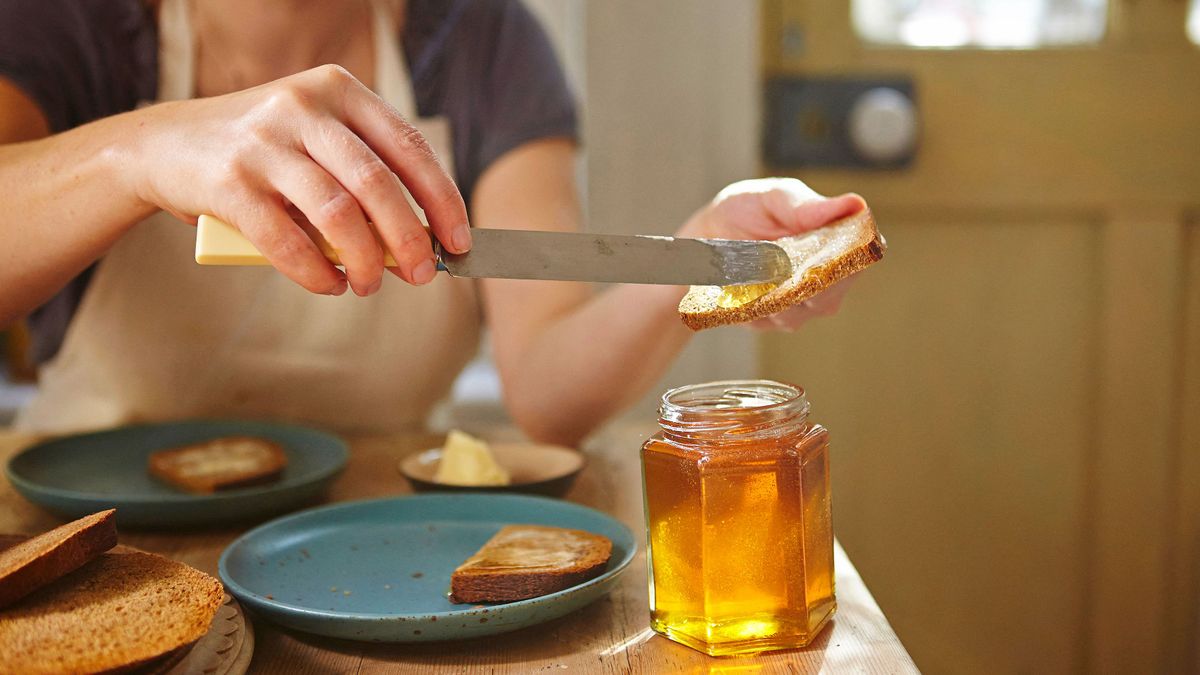 Woman tasting freshly extracted honey on bread (Photo by Janie Airey / Cultura Creative / Cultura Creative via AFP) méz