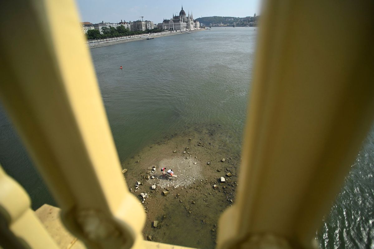 Budapest, 2022. augusztus 6.A csapadékhiány miatt alacsony a Duna vízállása, a Margitsziget déli csücske kiemelkedik a folyó vizéből a Margit híd alatt, Budapesten 2022. augusztus 6-án. Az ott lévő padon fiatalok ülnek.MTI/Balogh Zoltán
