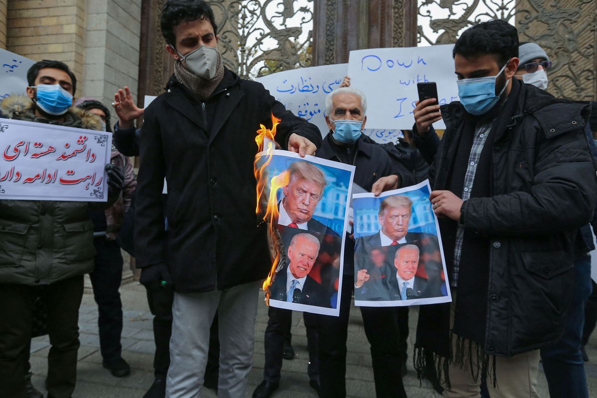 Students of Iran's Basij paramilitary force burn posters depicting US President Donald Trump (top) and President-elect Joe Biden, during a rally in front of the foreign ministry in Tehran, on November 28, 2020, to protest the killing of prominent nuclear scientist Mohsen Fakhrizadeh a day earlier near the capital. - Iran's President Hassan Rouhani accused arch-foe Israel of acting as a "mercenary" for the US and seeking to create chaos, blaming it for the assassination of a top Iranian nuclear scientist. (Photo by ATTA KENARE / AFP)