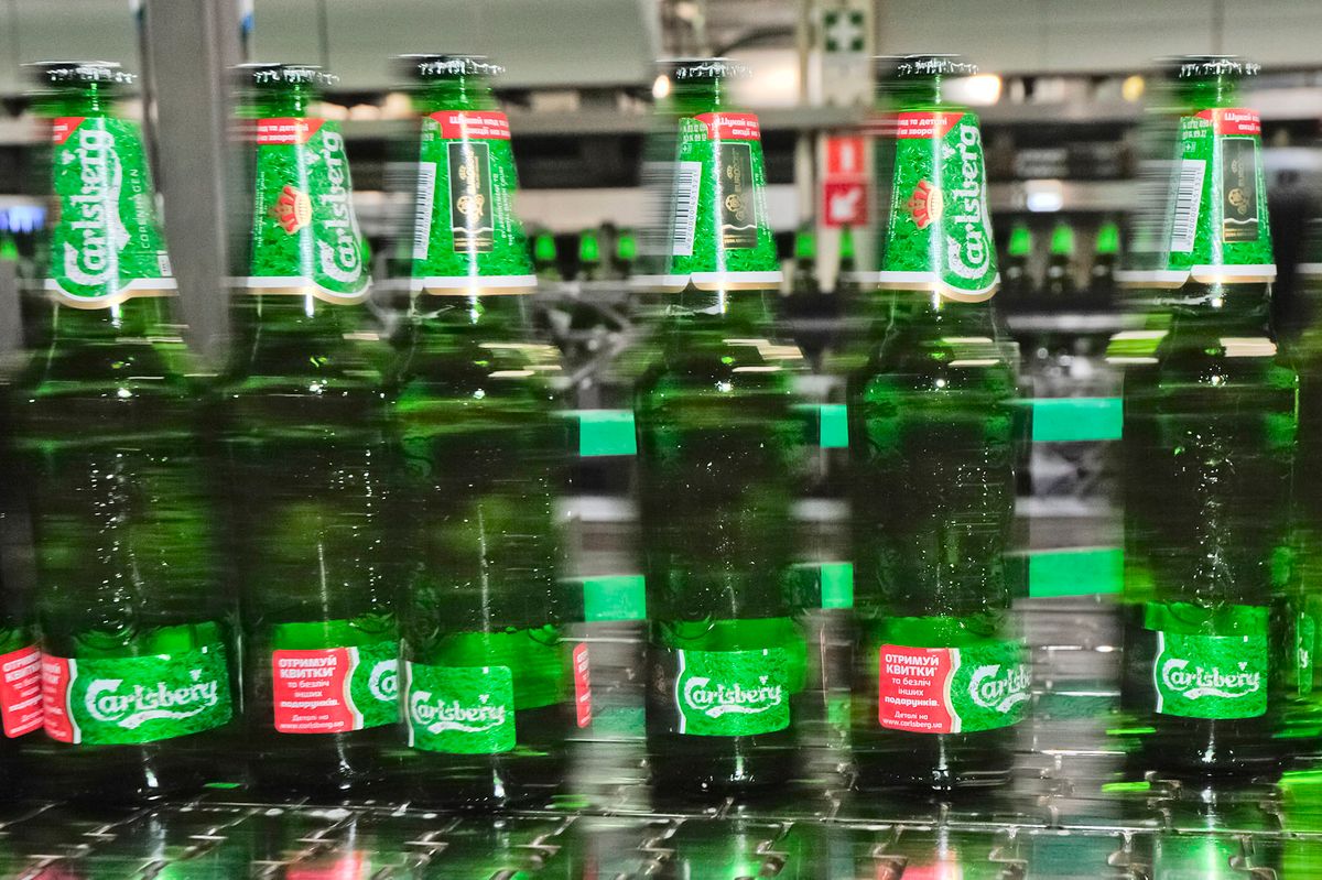 141294065 Bottles of lager move along a conveyor belt at the Carlsberg A/S production plant in Kiev, Ukraine, on Wednesday, March 14, 2012. Sales in the Ukraine were "significantly higher," helped by better economic conditions and the recent introduction of premium beers, while the U.K. saw "continuing strong growth," the brewer said. Photographer: Vincent Mundy/Bloomberg via Getty Images