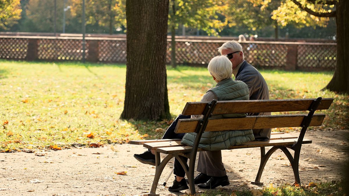 önkéntes nyugdíjpénztárak Full outdoor shot presenting autumn scenery. Retired senior couple sitting on the bench in park, enjoying beautiful weather. High quality photo