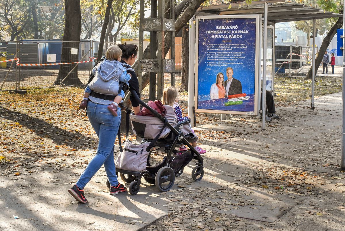 Budapest, 2019. október 27.
Egy fiatal anya germekeivel sétál egy babaváró támogatást hirdető plakát 
