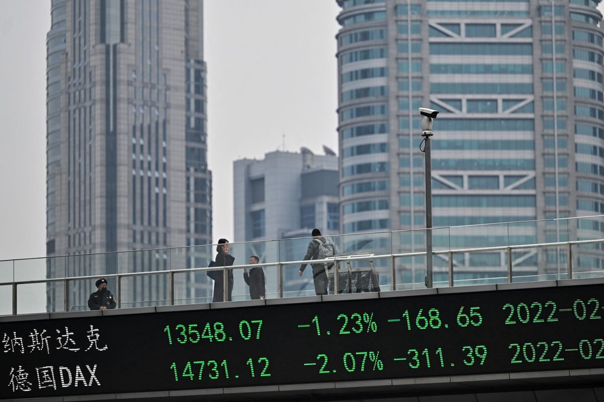 People walk across a bridge with a ticker board showing stock prices in the financial district of Shanghai on February 22, 2022.
HECTOR RETAMAL / AFP