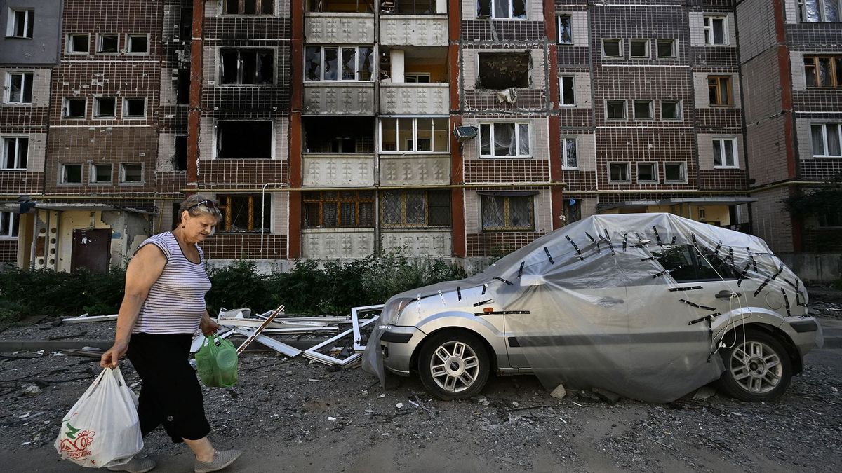 A woman gathers her belongings from a heavily damaged residential building in Saltivka, a northern district of the second largest Ukrainian city of Kharkiv on July 31, 2022, amid the Russian invasion of Ukraine. (Photo by Genya SAVILOV / AFP)