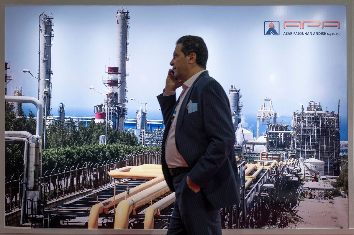 Two years after the COVID-19 outbreak in Iran, An Iranian visitor speaks on his cellphone while walking past an image of gas facilities at the 26th International Oil, Gas, Refining and Petrochemical Exhibition in Tehran on May 13, 2022. 