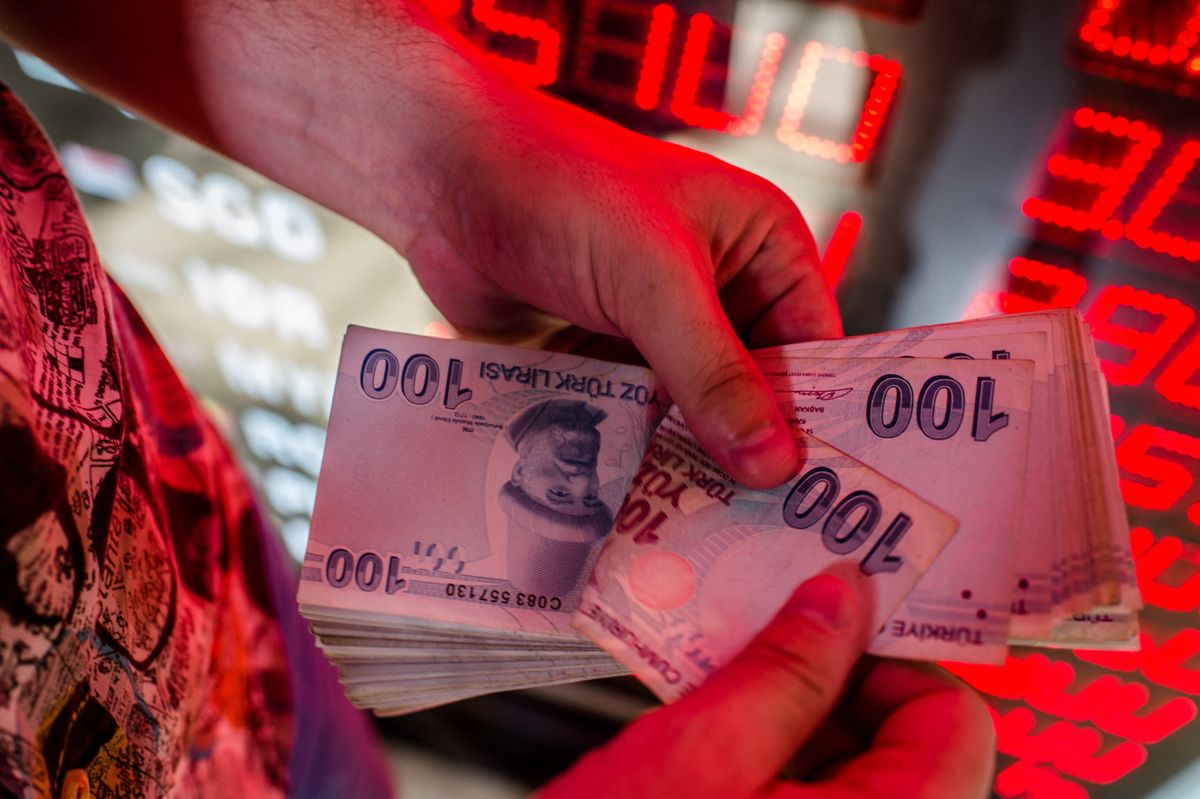 (FILES) In this file photo taken on August 8, 2018, a money changer counts Turkish lira banknotes at a currency exchange office in Istanbul, on August 8, 2018. - Turkey's central bank on August 18, 2022, stunned the markets by lowering its main interest rate even as inflation soared to a 24-year high and looks set to climb further. The central bank said "recession is increasingly assessed as an inevitable risk factor" as it lowered its one-week repo auction rate to 13 percent from 14 percent. (Photo by Yasin AKGUL / AFP)