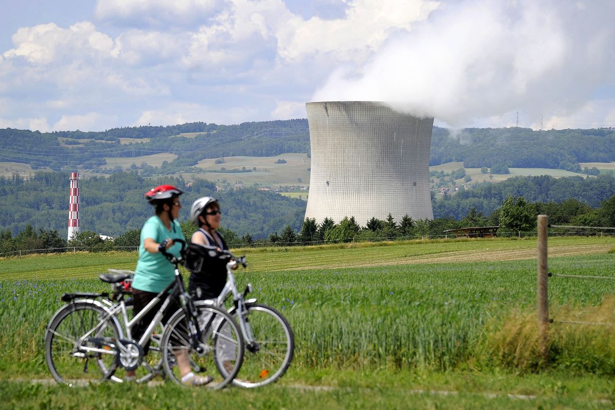 In this picture taken on May 22, 2011 two women walk in front of Leibstadt nuclear power plant near Leibstadt, northern Switzerland. The Swiss government announced on May 25, 2011 to recommend to parliament that the country's five nuclear power plants should not be replaced as they age, leaving them to be phased out by 2034. "The federal council wishes to continue guaranteeing high security for energy supply in Switzerland, but without nuclear in the medium term," an official statement said after the meeting of the seven-member cabinet.  AFP PHOTO / FABRICE COFFRINI (Photo by FABRICE COFFRINI / AFP)