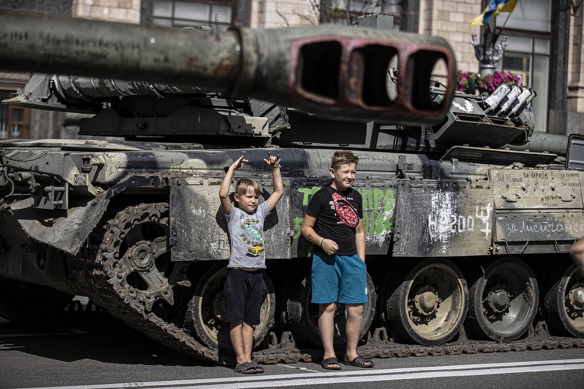 KYIV, UKRAINE - AUGUST 24: Ukrainian kids pose for a photo with a tank, captured by Ukrainian forces during the war against Russia, on Khreshchatyk street during the Ukraine's 31st Independence Day in Kyiv, Ukraine on August 24, 2022. Although public celebrations, meetings and demonstrations with large participation were banned on August 22-25 due to the fear that Russia might attack Kiev, Ukrainian people came to the area where the military vehicles captured in the war were exhibited. Metin Aktas / Anadolu Agency (Photo by Metin Aktas / ANADOLU AGENCY / Anadolu Agency via AFP)