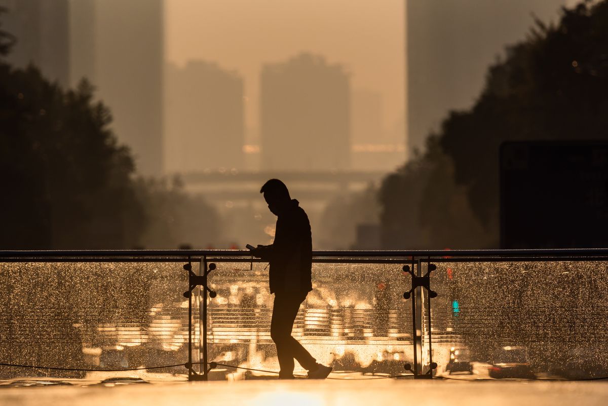 Silhouette of a man walking on a foot bridge against sunrise in downtown Chengdu city, Silhouette of a man walking on a foot bridge against sunrise in downtown Chengdu city, Sichuan  province, China