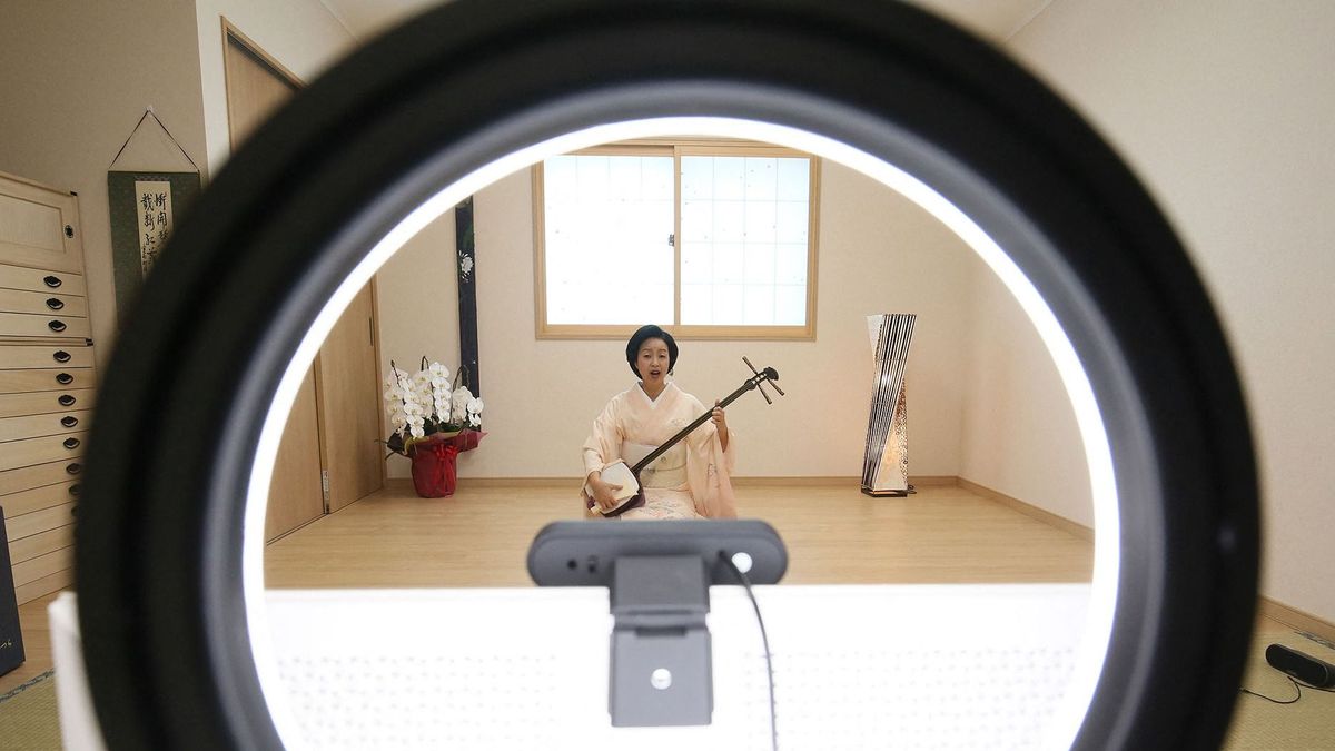 Geisha Yumiko prepares to play the shamisen from her home in Hakone, Kanagawa Prefecture, on Aug. 8, during a Meet Geisha Online Drinking session with a couple in the United States.Amid plunging demand because of the spread of the novel coronavirus, struggling geisha in Hakone, Kanagawa Prefecture, have focused their attention on online services to entertain customers with conversation and traditional performances.During an online event dubbed Meet Geisha Online Drinking, geisha in the town well-known for its onsen hot spring resort use the videoconferencing service Zoom to interact with groups of customers. Participants have their own alcoholic beverages or soft drinks and, through their computer or smartphone screens, watch as the geisha play the shamisen or perform traditional dance.The cost for a 30-minute session is Ą1,650 per person for Japanese speakers and Ą2,000 per person in English. Each group in English is required to have at least three people, however, as two customers can form a group by paying the fee for three people. ( The Yomiuri Shimbun ) (Photo by Ryuzo Suzuki / Yomiuri / The Yomiuri Shimbun via AFP)