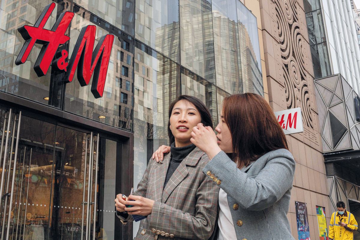 People walk past a store of Swedish clothing giant H&M in Beijing on March 25, 2021. (Photo by NICOLAS ASFOURI / AFP)
