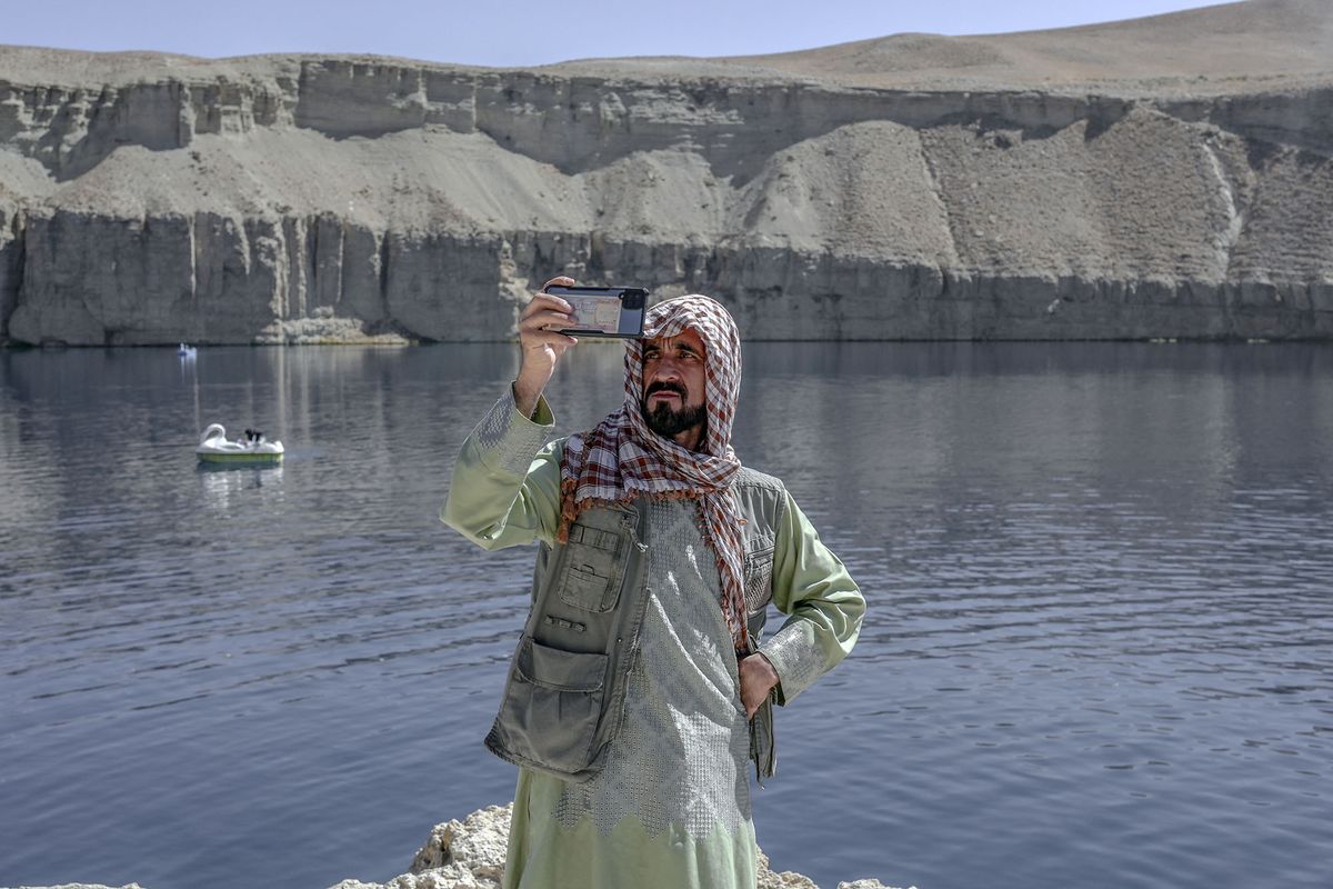 A man takes a video with his mobile phone next to the Band e-Amir lake in the Bamiyan Province on October 4, 2021. - The stunning azure waters of the Band-e Amir lakes are once again attracting Afghan tourists, who brave bumpy roads to experience the so-called Grand Canyon of Afghanistan. (Photo by BULENT KILIC / AFP) / TO GO WITH AFP STORY Afghanistan-tourism by Emmanuel PEUCHOT