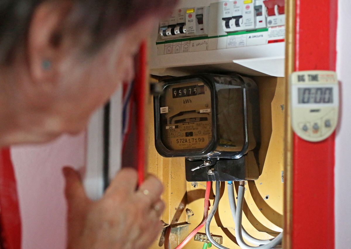 Energy customer Diane Skidmore examines her electricity meter in her flat on the south London estate where she lives, on August 25, 2022. - Increasingly cash-strapped Britons learn Friday, August 26, how much their electricity and gas bills will rise in October, as the regulator unveils its latest energy price cap that could tip millions into fuel poverty. (Photo by Susannah Ireland / AFP)