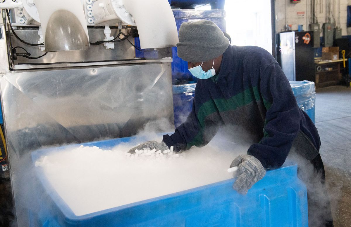 An employee makes dry ice pellets at Capitol Carbonic, a dry ice factory, in Baltimore, Maryland, November 20, 2020. - Amid a whipsaw year that saw a surge in demand for its dry ice and a shortage of the carbon dioxide needed to make it, Capitol Carbonic received a call from a prospective customer: Pfizer. The global pharmaceutical giant was on the hunt for the quarter-inch pellets Capitol Carbonic, a six-decade-old family concern, spits out of a machine resembling a giant spaghetti maker in a Baltimore warehouse -- exactly what Pfizer needs to keep its Covid-19 vaccine at just the right, very chilly, temperature. (Photo by SAUL LOEB / AFP)