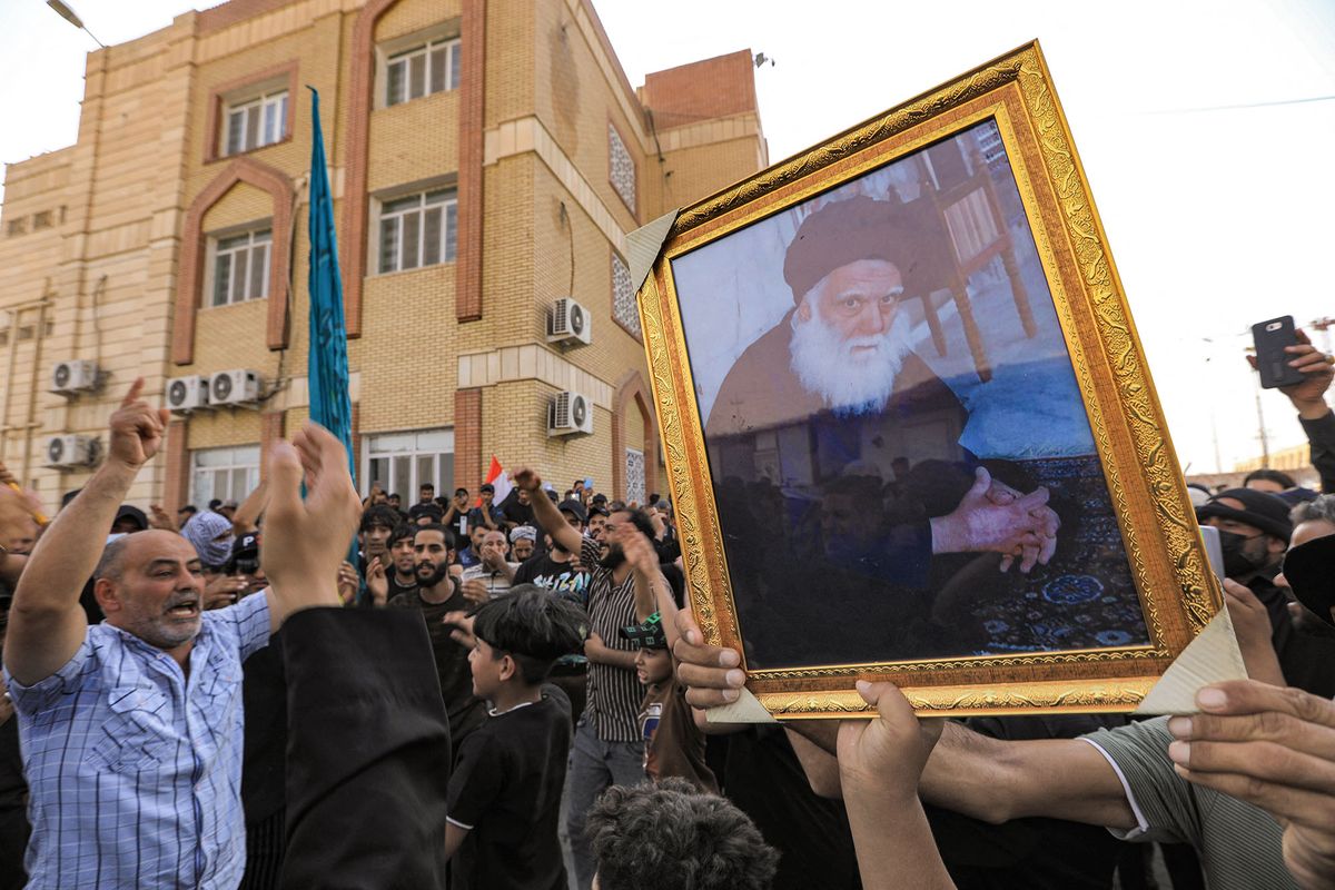 Supporters of Iraqi Shiite cleric Moqtada Sadr raise a portrait of his father the late Grand Ayatollah Mohammed Sadeq al-Sadr as they gather in the grounds of the local government headquarters in the city of Nasiriyah in Iraq's southern Dhi Qar province on August 29, 2022. - Iraq declared a nationwide curfew after two protesters were killed in the capital Baghdad as supporters of Moqtada Sadr stormed the government palace in the heavily-fortified Green Zone on August 29 following the powerful Shiite leader's declaration that he was quitting politics. (Photo by Asaad NIAZI / AFP)