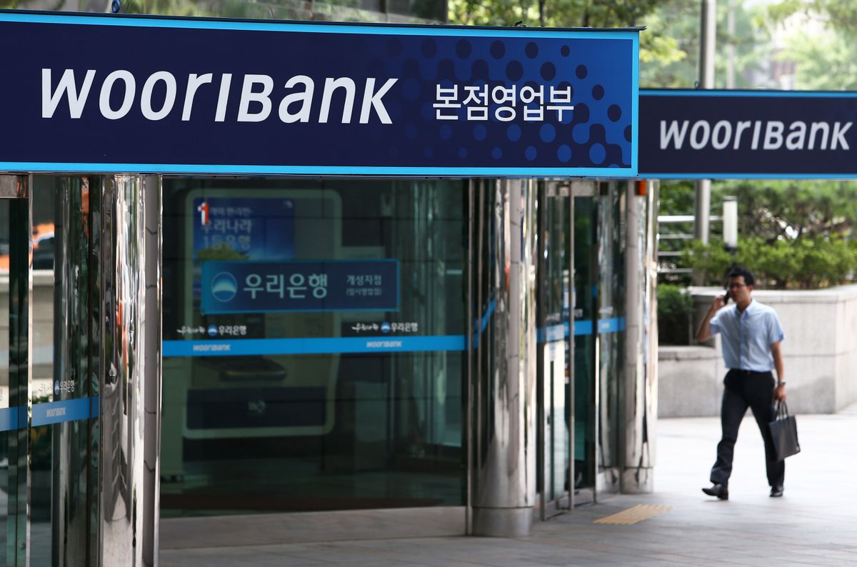 Images Of Woori Finance Ahead Of Earnings, A man walks past the Woori Bank Co. headquarters, a unit of Woori Finance Holdings Co., in Seoul, South Korea, on Friday, July 26, 2013. Woori Finance is scheduled to announce second-quarter earnings next week. Photographer: SeongJoon Cho/Bloomberg via Getty Images