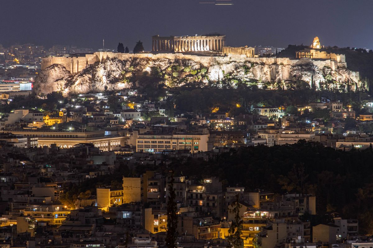 Night view of the Parthenon and Acropolis in the Greek capital Athina. Long exposure photography showing the antiquities illuminated in the dark with the urban landscape of the city around. The ancient hill of Acropolis, including the worldwide known marble made temple Parthenon and remains of many ancient buildings of great architectural and historic significance as the Erechtheion, Propylaia, Temple of Athena Nike, the Caryads and more. Acropolis was severed heavy damage during the Ottoman occupation. It is nowadays UNESCO World Heritage site since 1987. The Parthenon was a temple dedicated to the ancient Greek goddess Athena, it was built in 432BC by the architects Iktinos and Calicrates. There were also famous sculptures from Phidias inside. Athens, Greece on August 25, 2020 (Photo by Nicolas Economou/NurPhoto) (Photo by Nicolas Economou / NurPhoto / NurPhoto via AFP)