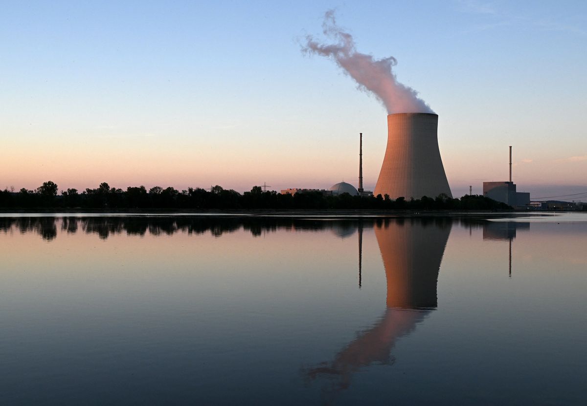 The Isar Nuclear Power Plant with its cooling tower reflects in the river Isar in Essenbach near Landshut, southern Germany, on August 3, 2022. - German Chancellor Olaf Scholz on August 3, 2022 raised the possibility of keeping nuclear plants going. Extending the lifetime of the plants has set off a heated debate in Germany, where nuclear power has been a source of controversy. Former chancellor Angela Merkel spectacularly decided to ditch atomic energy in 2011 following the Fukushima nuclear disaster in Japan.