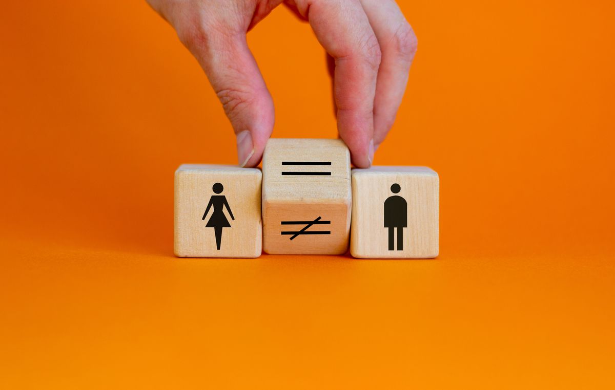 Symbol,For,Gender,Equality.,Hand,Turns,A,Cube,And,Changes, Symbol for gender equality. Hand turns a cube and changes a unequal sign to a equal sign between symbols of men and women. Beautiful orange background, copy space. Gender equality concept. Symbol for gender equality. Hand turns a cube and changes a unequal sign to a equal sign between symbols of men and women. Beautiful orange background, copy space. Gender equality concept.