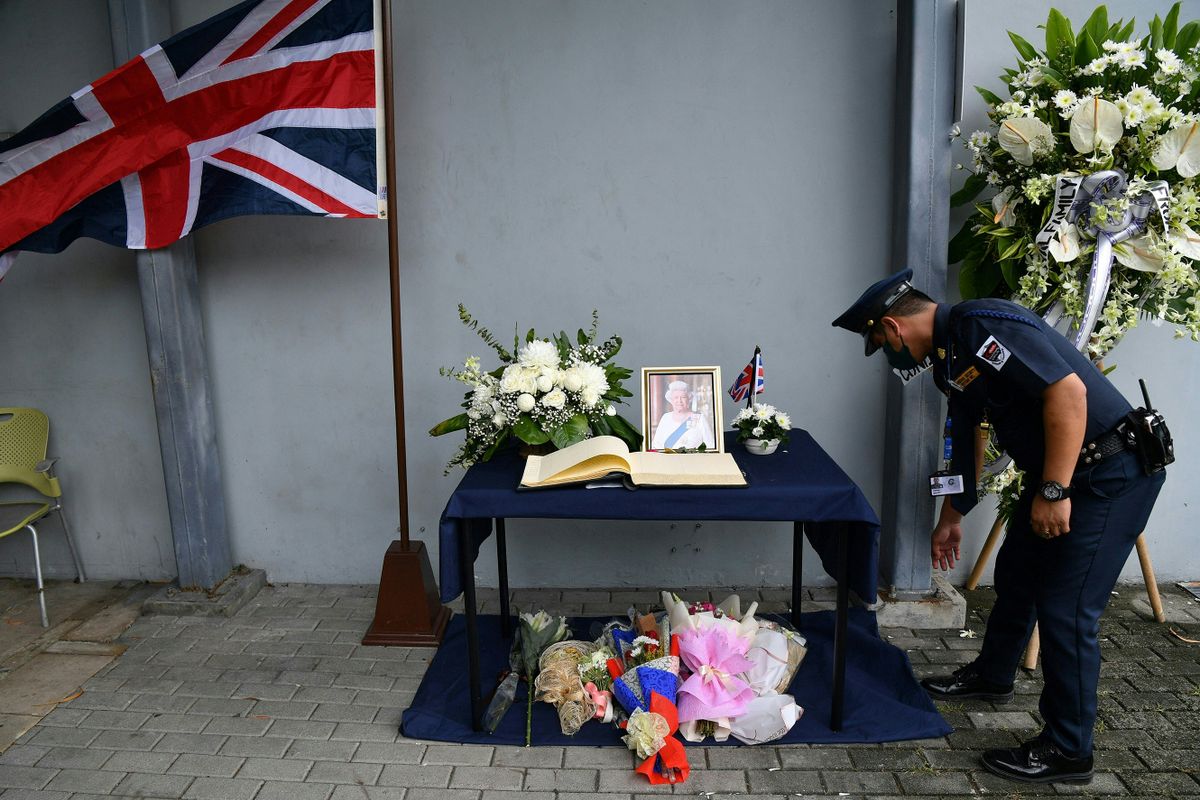 A security guard stands next to the condolence book at the British embassy in Manila on September 12, 2022, following the passing of Britain's Queen Elizabeth II on September 8 aged 96.