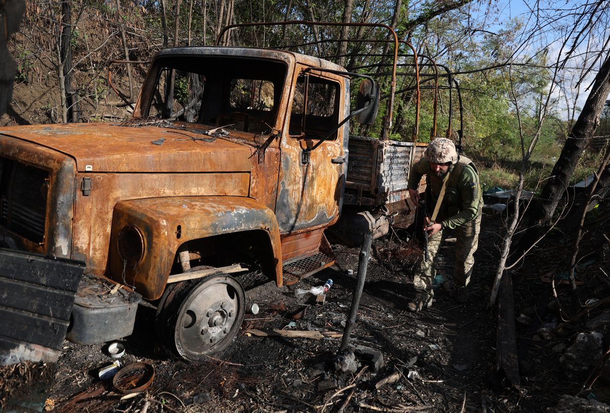 A Ukrainian soldier walks by a burnt vehicle at the frontline with Russian troops in Donetsk region on September 23, 2022